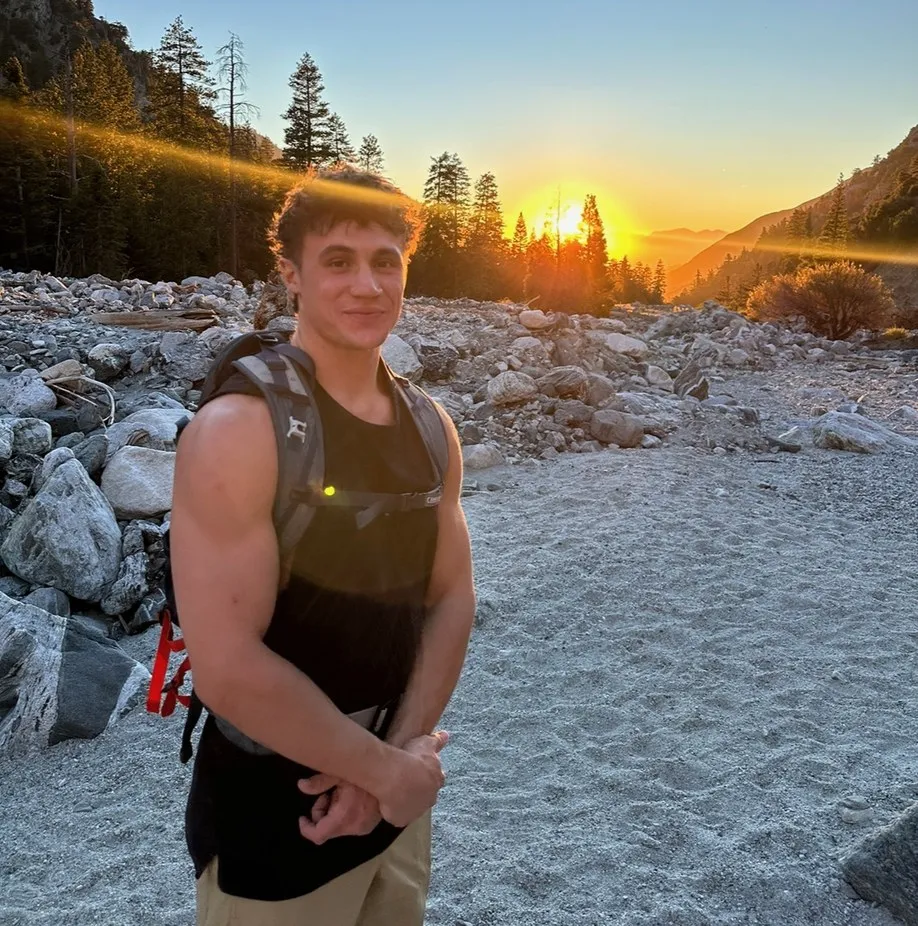 Jack, a Webflow designer, standing at a mountain riverbed at sunset.